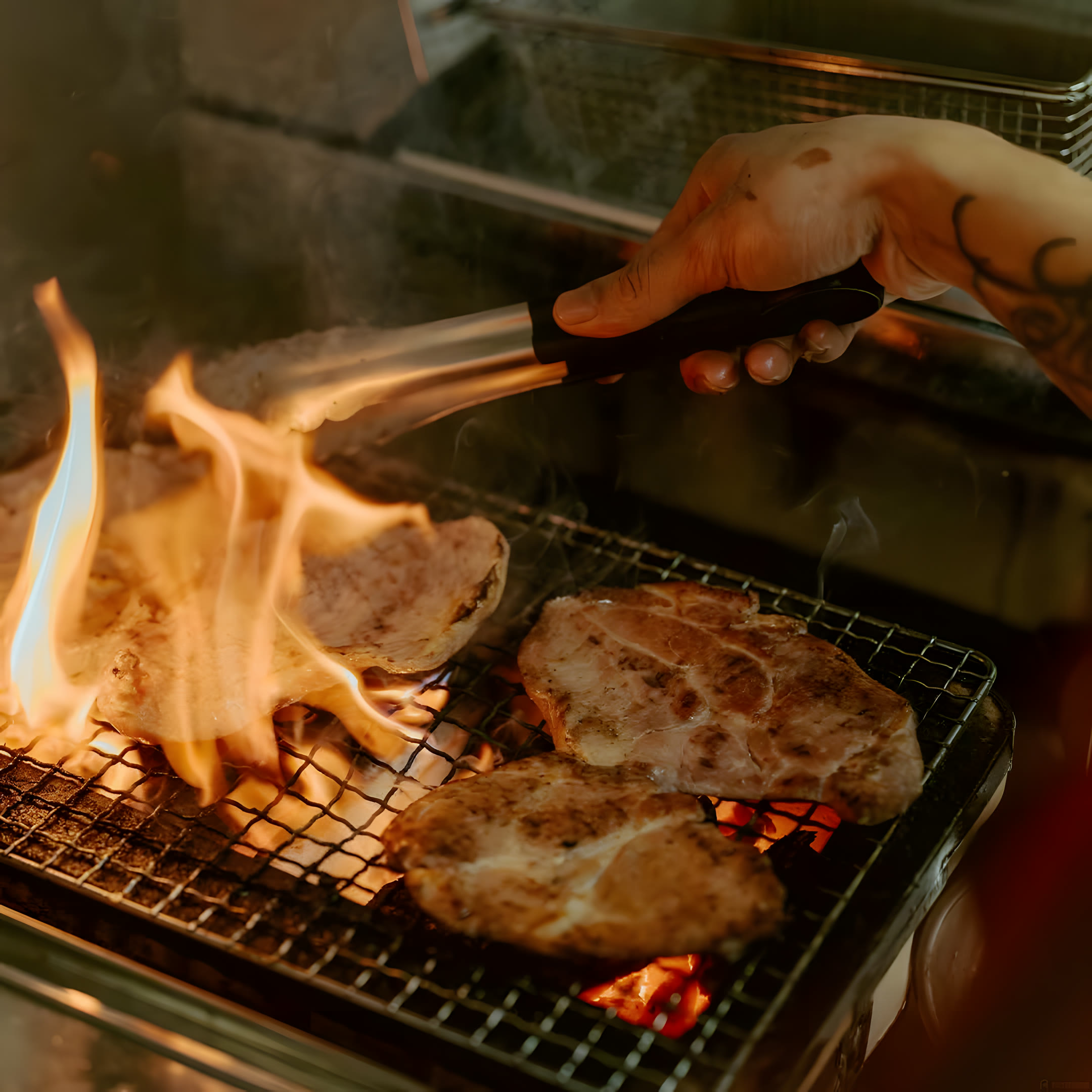 Pork collar searing over open charcoal flames at Dilly Deli, Taman Connaught